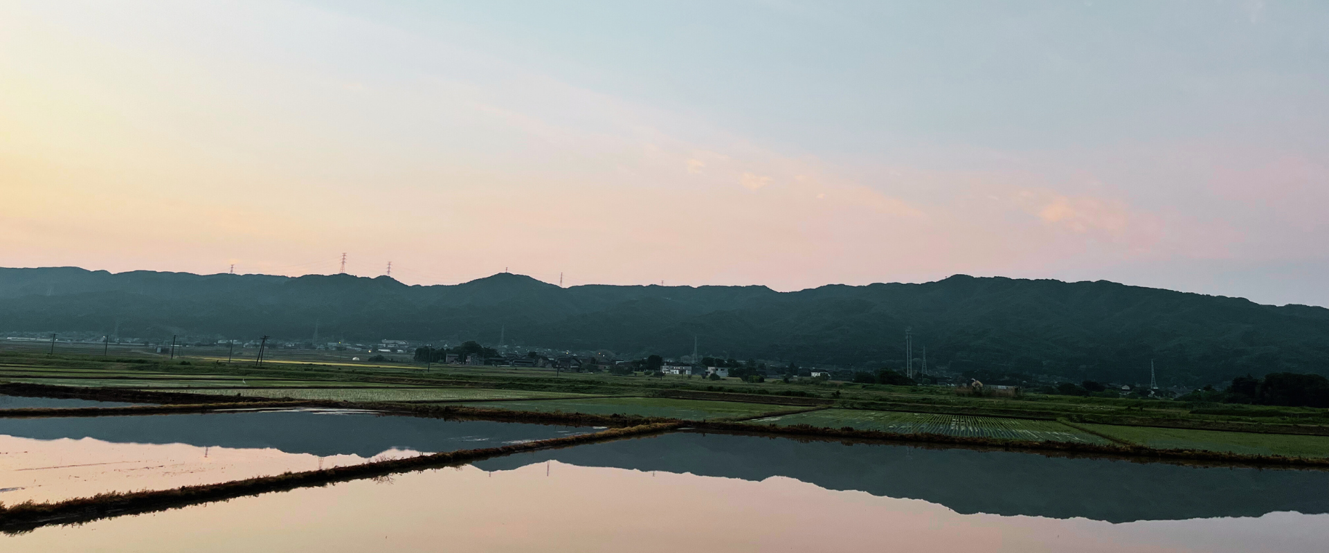 田んぼの湖面に山並みが写っている風景